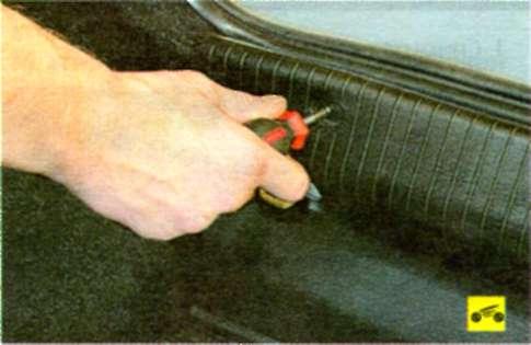 Для зняття задньої облицювання багажника зніміть чотири гвинти кріплення