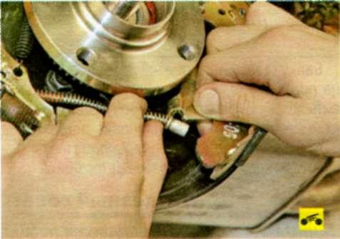 Отсоедините задние тросы стояночного тормоза от разжимных рычагов тормозных механизмов задних колес
